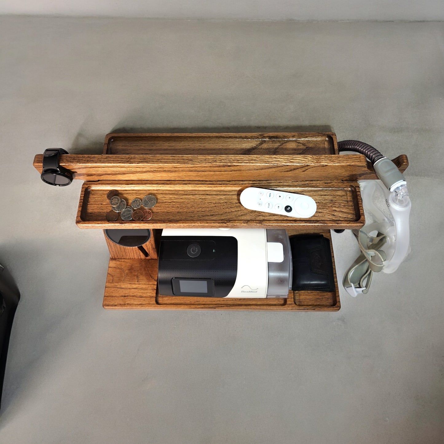 A top view of the CPAP Smart Stand made by Custom Cave Works. The stand is made from solid Oak wood and shows a very organized view of the catch-all trans, including the one on the back side of the stand.