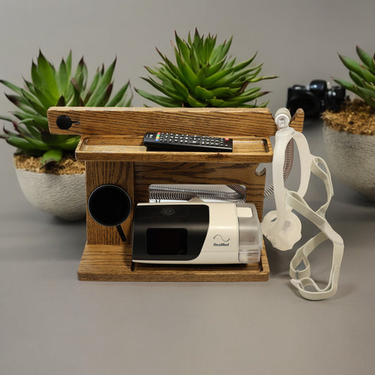 A CPAP Smart Stand that has the CPAP inserted and mask hanging from the stand.  This stand also includes the optional wireless phone charger.