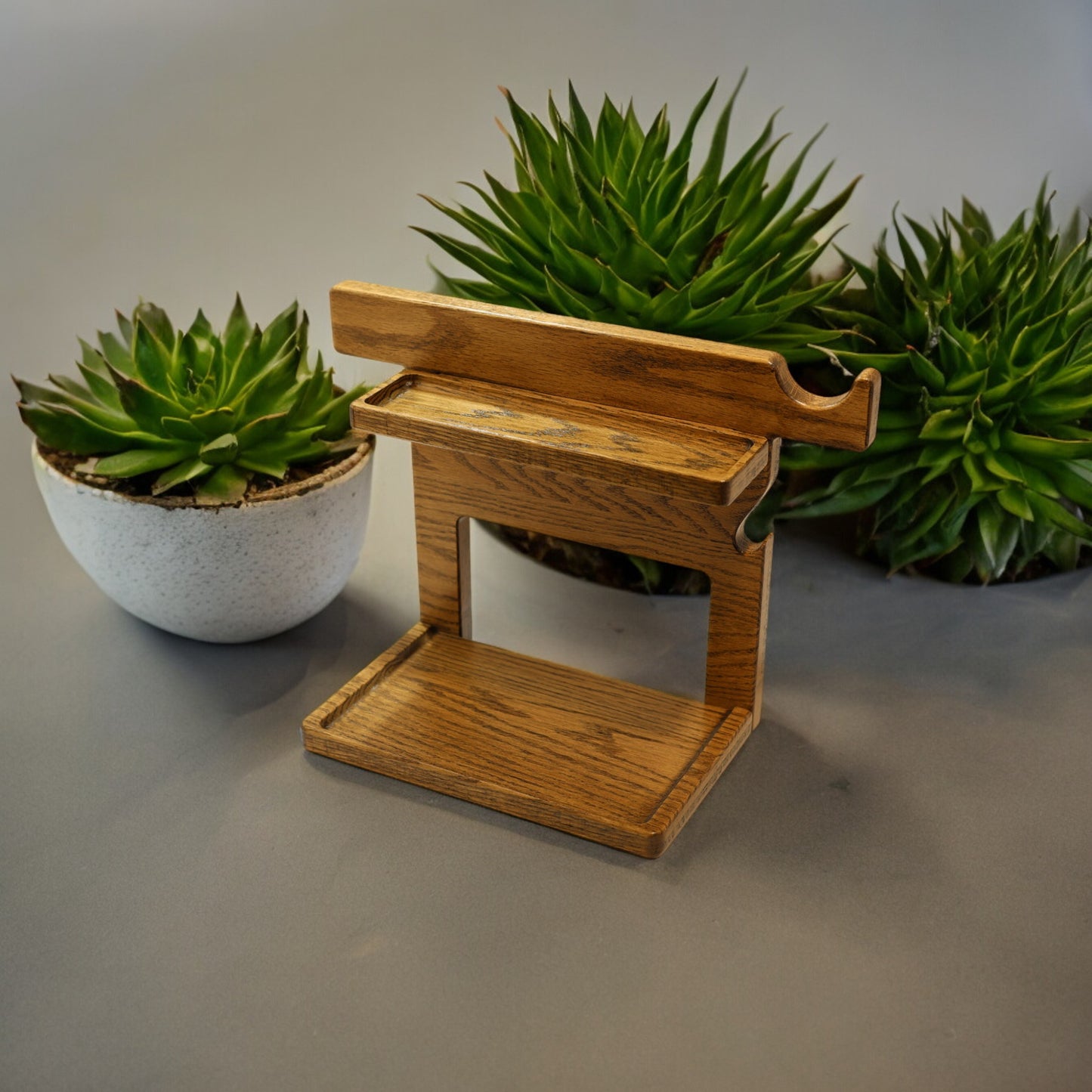 An empty CPAP Stand made by Custom Cave Works. The stand is next to some greens and includes catch-all trays to keep your nightstand organized. The stand is sold oak wood that has a satin finish.