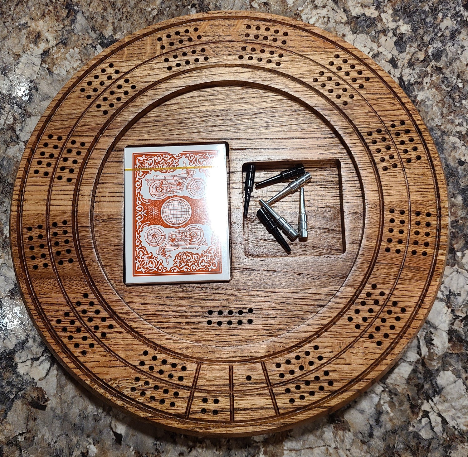 Pitchard is the bottom half of a round cribbage board milled from a solid piece of red oak.  There are peg holes, a pocket to store the cards and a pocket to store the pegs.  